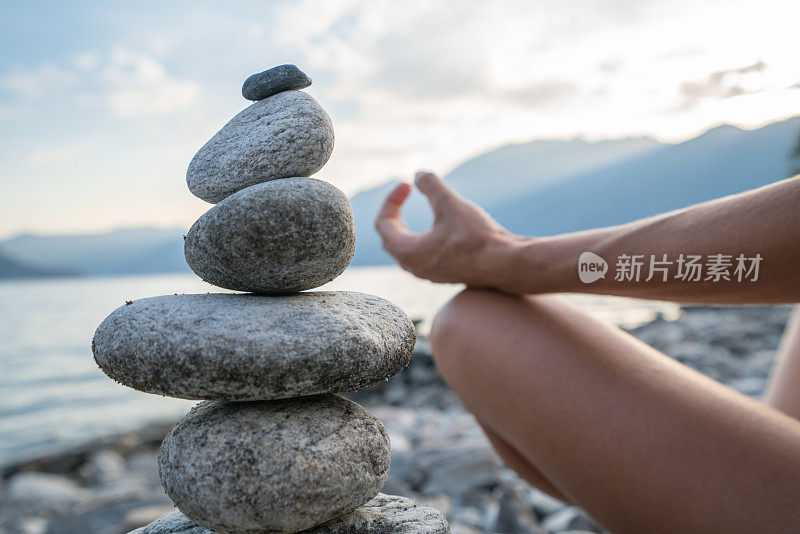 日落时分在湖边的stack rock附近练习瑜伽和冥想的人的细节